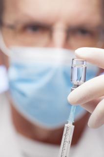 Arzt zieht Impfstoff auf eine Spritze