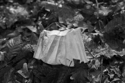 Atemschutzmaske am Boden liegend achtlos weggeworfen im Wald