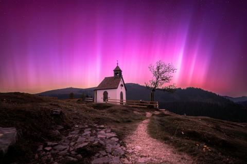 Eine kleine Kapelle in den Alpen unter den Nordlichtern