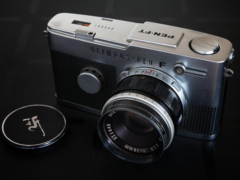 Vorbild für das Design war die erste Olympus F, die in den 1960ern von Olympus hergestellt wurde. Hier zu sehen ist eine Olympus Pen FT, hergestellt zwischen 1966 und 1972.