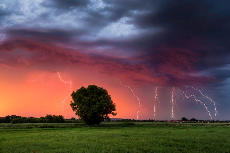 Gewitterzelle bei Sonnenuntergang. Eine Lichtstimmung, die der Wetterfotograf Bastian Werner so in Deutschland noch nicht fotografiert hatte. Blitze zuckten über dem Himmel, während das rote Licht der Sonne die Landschaft einhüllte.