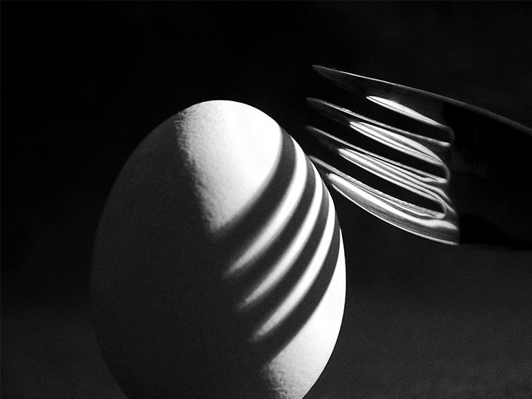 Schatten einer Gabel auf einem Ei.