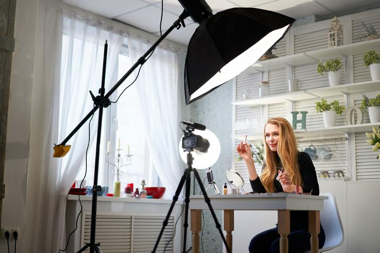 Beauty-Bloggerin filmt Make-up-Routine-Tutorial vor der Kamera.