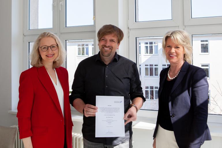 FHM-Rektorin Prof. Dr. Anne Dreier (rechts) und Medien-Dekanin Prof. Dr. Astrid Kruse (links) überreichten Stefan Finger die Urkunde zur Professur.