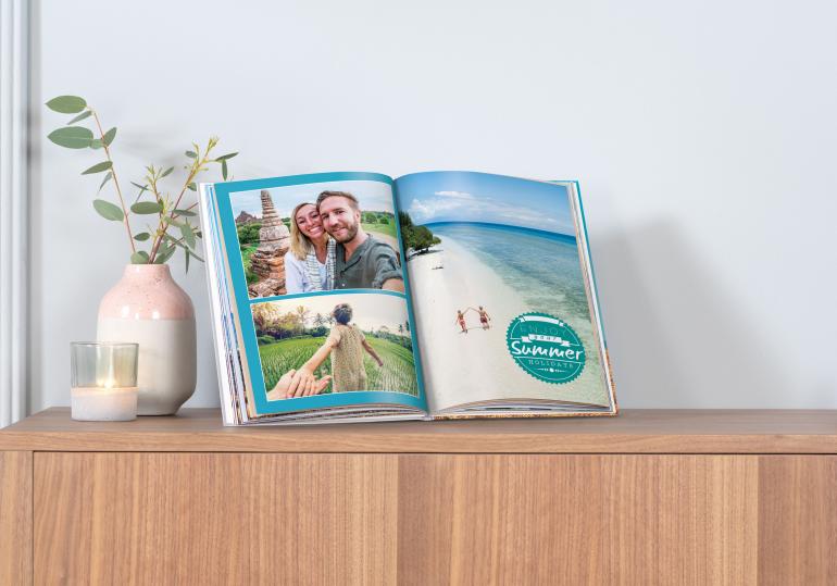 Aufgeschlagenes Pixum-Fotobuch auf einem Sideboard.