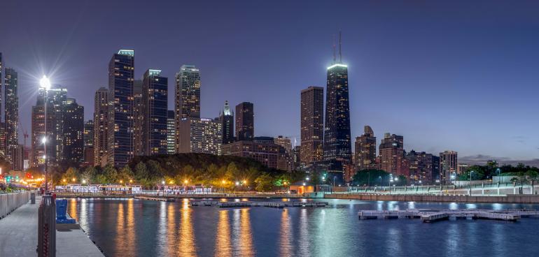 Die beleuchtete Skyline spiegelt sich im ruhigen Wasser – eine gelungene Komposition aus Stadtlandschaft, Licht und Spiegelung. Das Panorama entfaltet bei Dämmerung seine volle Wirkung.