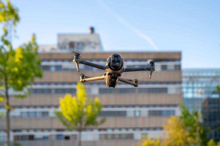 Die DJI Mavic 4 Pro im Schwebeflug vor urbaner Kulisse – präzise Positionierung und stabile Fluglage dank fortschrittlicher Sensorik und Hinderniserkennung.
